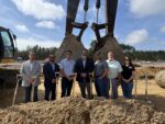 Group of seven people standing with shovels at a construction site.