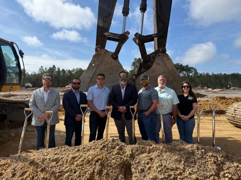 Group of seven people standing with shovels at a construction site.